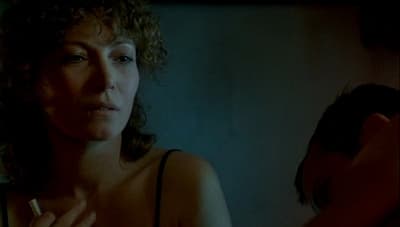 a woman with curly hair smoking a cigarette
