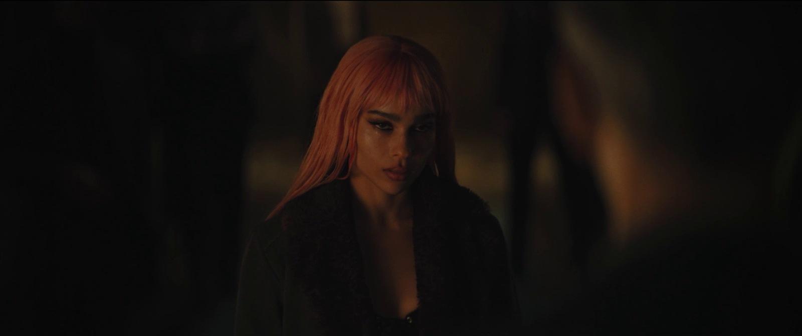 a woman with red hair standing in a dark room