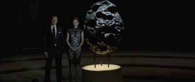 a man and a woman standing in front of a sculpture