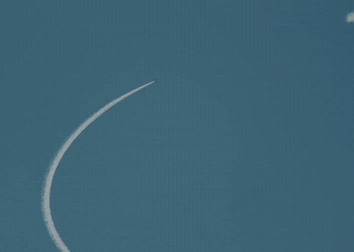 an airplane flying in the sky leaving a contrail