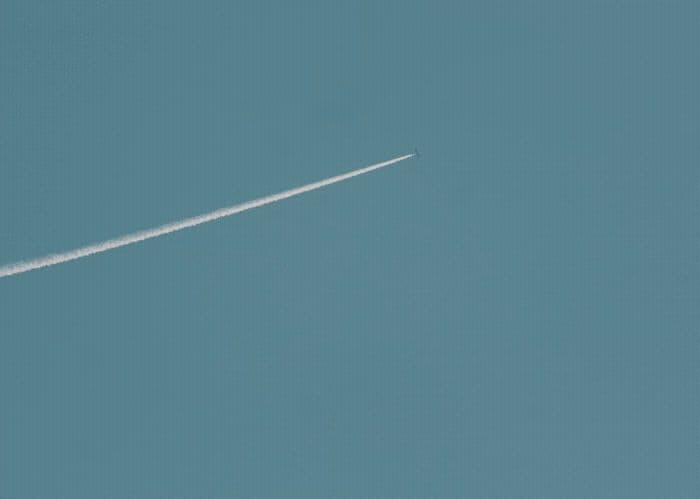 an airplane flying in the sky with a contrail