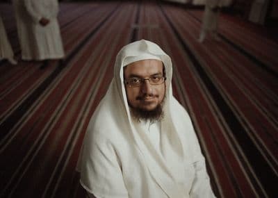 a man with a beard and glasses sitting in a room