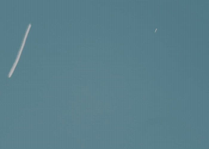 a plane flying in the sky with a contrail in the sky