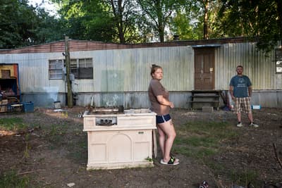 a woman standing next to a stove in a yard