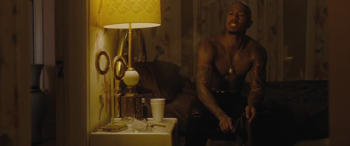 a man sitting on a bed next to a lamp