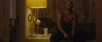 a man sitting on a bed next to a lamp