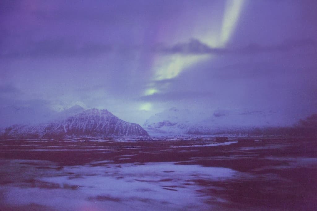 the aurora bore is visible in the sky above the mountains