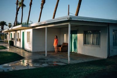 a woman in a red dress standing in front of a house