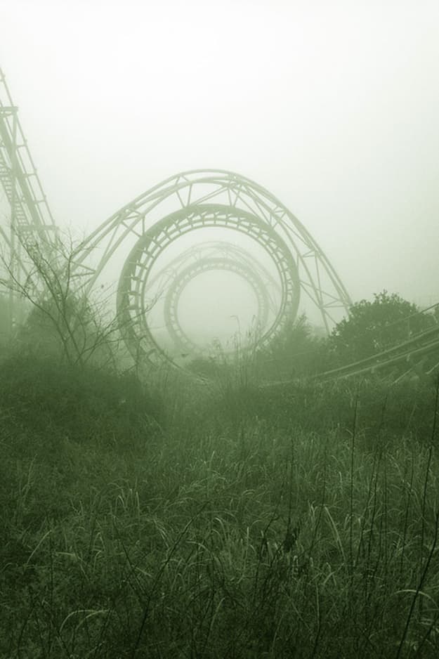 an amusement park in the fog with a roller coaster in the background