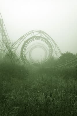 an amusement park in the fog with a roller coaster in the background