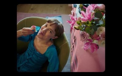 a woman sitting in a chair next to a vase of flowers