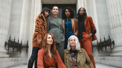 a group of women standing next to each other in front of a building