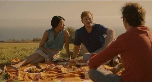 a group of people sitting on top of a grass covered field