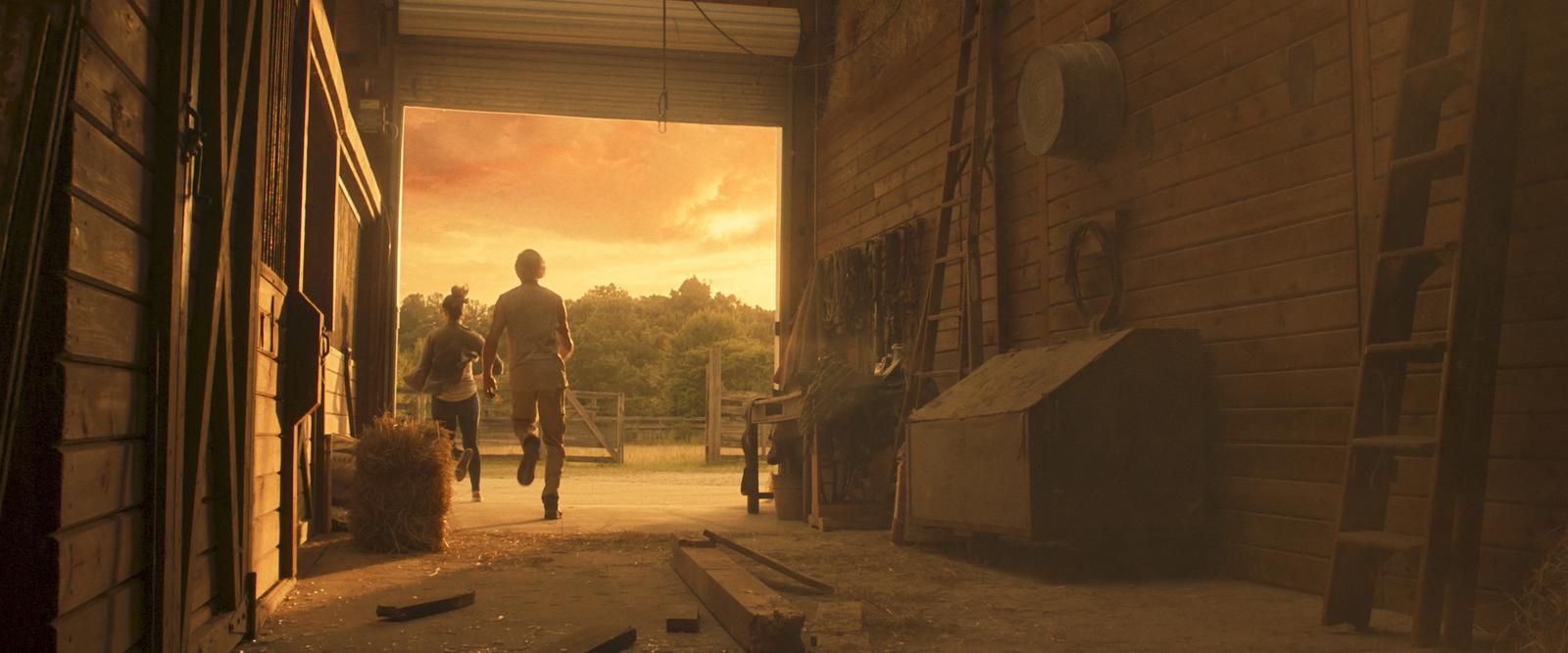 a couple of people that are walking out of a barn