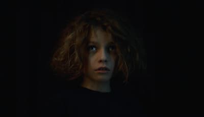 a woman with long hair standing in the dark