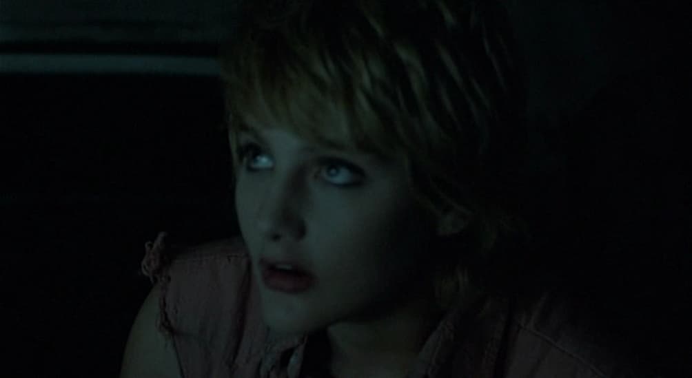 a woman with blue eyes sitting in the dark