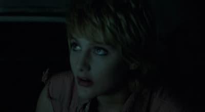 a woman with blue eyes sitting in the dark