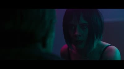 a woman in a dark room looking at a man