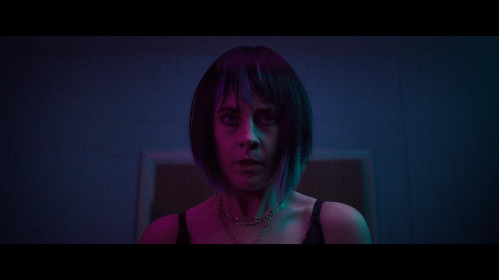 a woman in a dark room with a necklace on