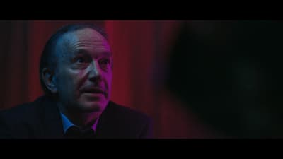 a man in a suit and tie looking at another man