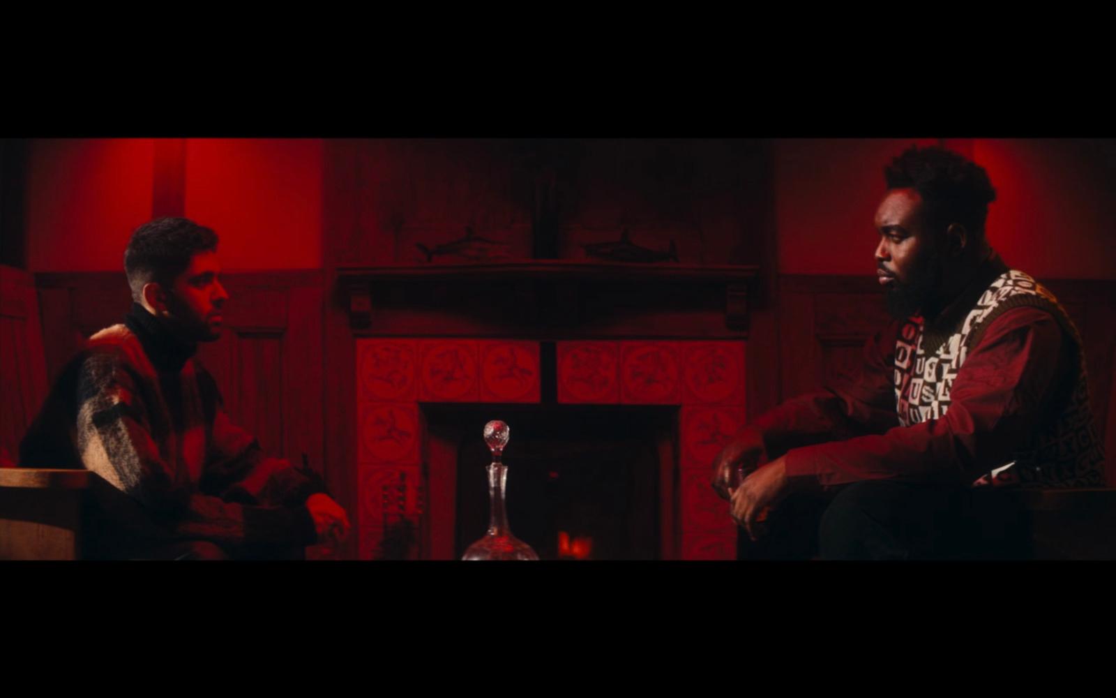 two men sitting next to each other in front of a fireplace