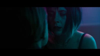 a woman is looking at another woman's face in the dark