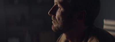 a man with a goatee stares into the distance