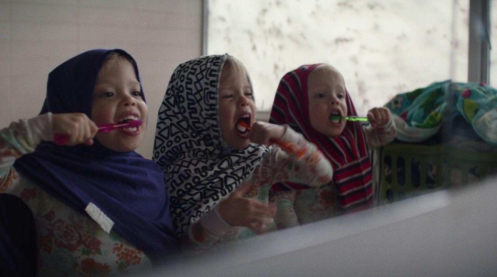 two women and a baby brushing their teeth