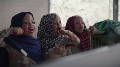 two women and a baby brushing their teeth