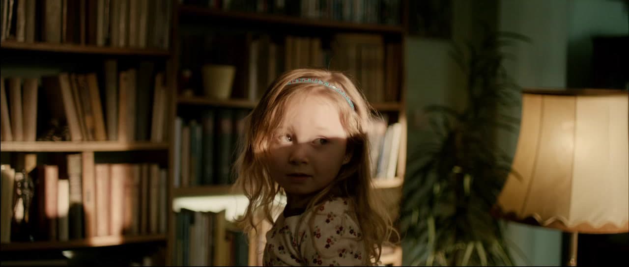 a young girl standing in front of a bookshelf