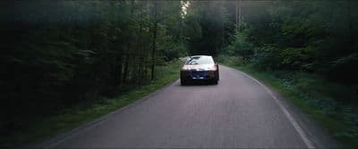 a car driving down a road next to a forest