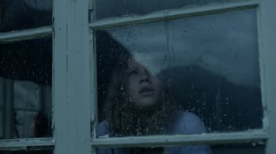 a woman looking out of a window in the rain