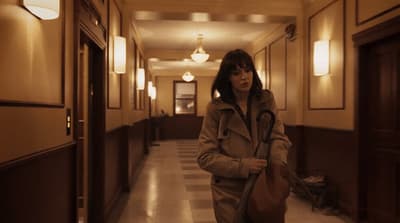 a woman walking down a hallway with a bag