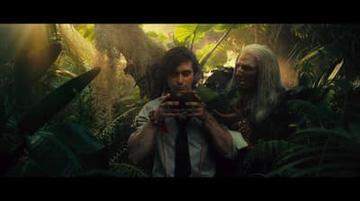 a man holding a cell phone in a jungle
