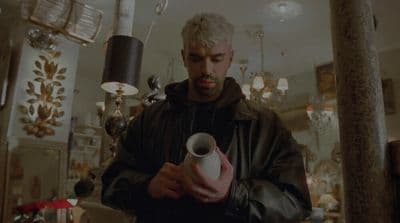 a man holding a white vase in a room