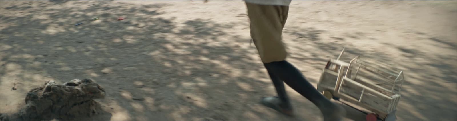a man walking down a dirt road next to a wooden bench