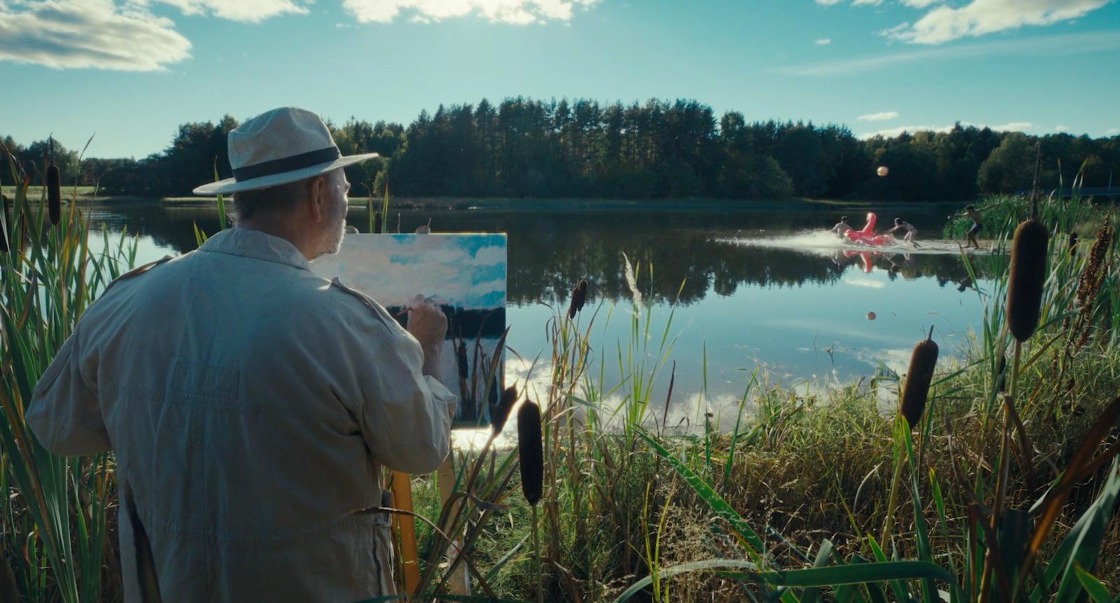 a man in a hat is painting on a canvas