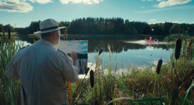 a man in a hat is painting on a canvas