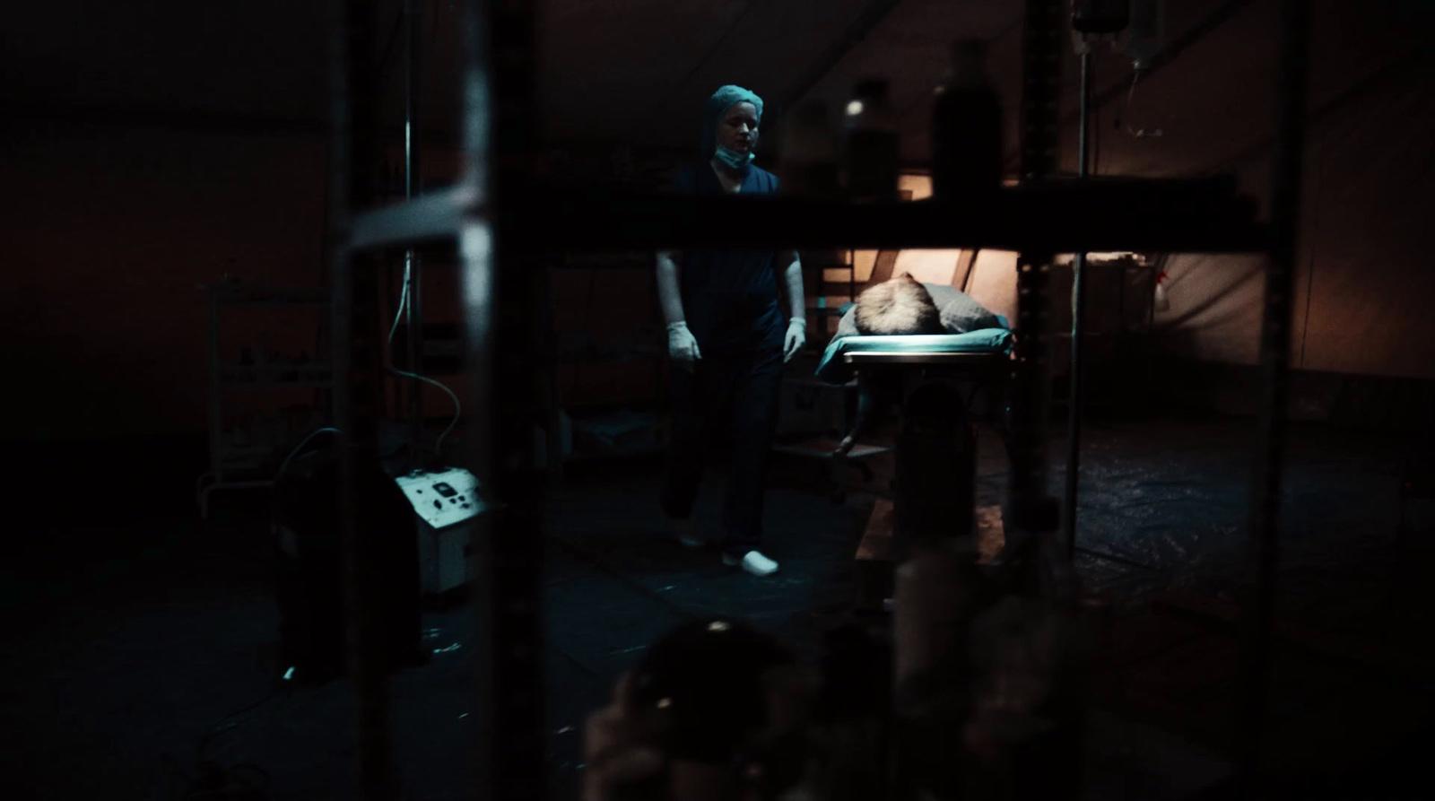 a man standing next to a bed in a dark room