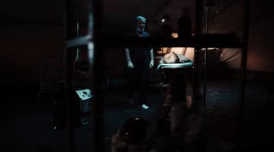 a man standing next to a bed in a dark room