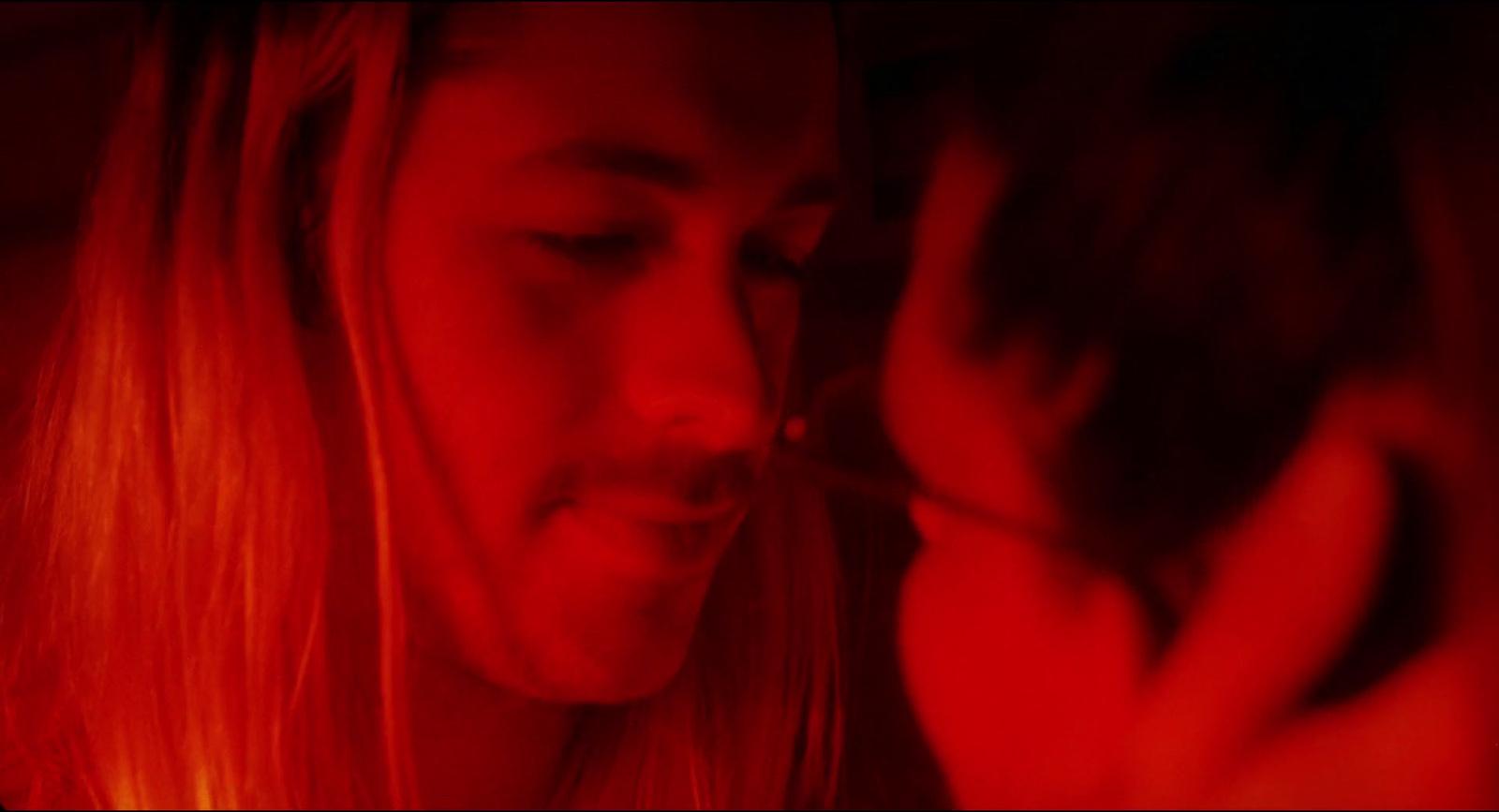 a man with long blonde hair holding a cell phone to his face