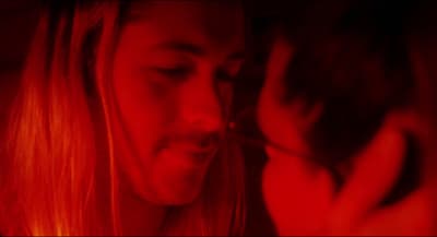 a man with long blonde hair holding a cell phone to his face