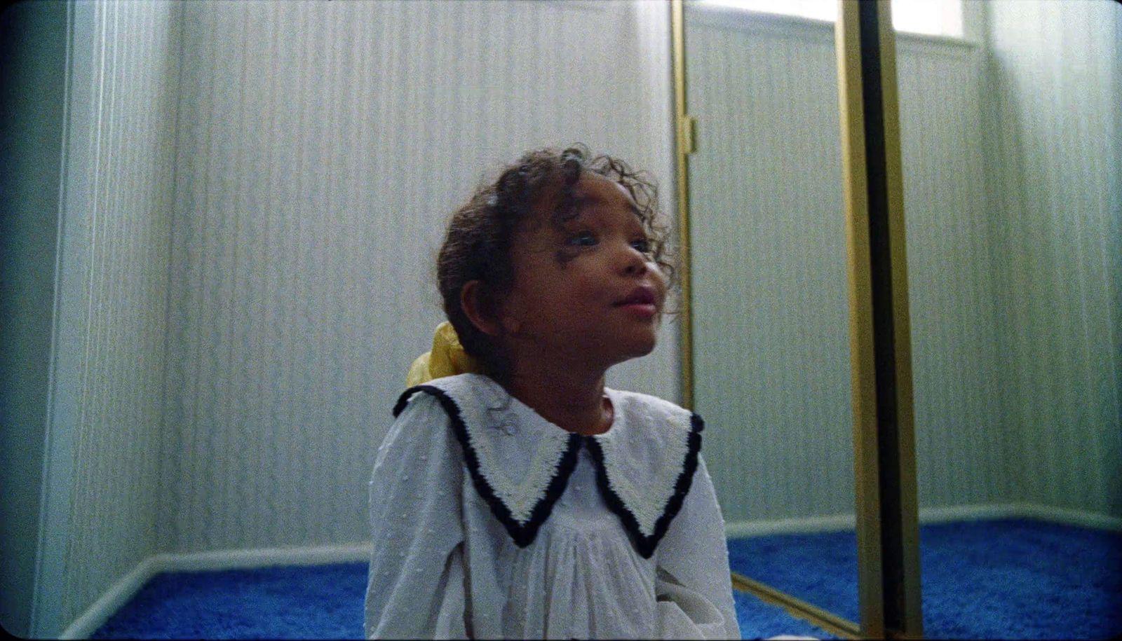 a little girl that is standing in front of a mirror