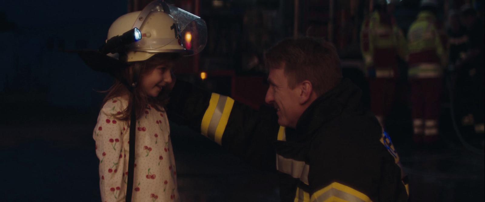 a fireman and a little girl standing next to each other