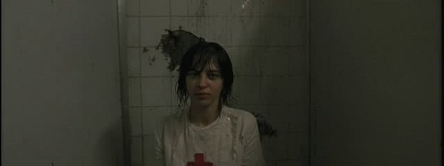 a woman standing in a bathroom with a cross on the floor