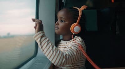 a little girl wearing headphones looking out a window
