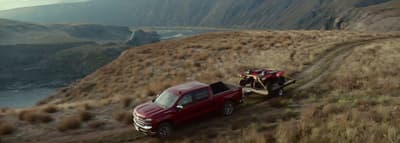 a red truck pulling a trailer down a hill
