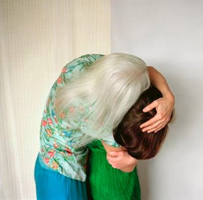 a woman in a green dress leaning against a wall