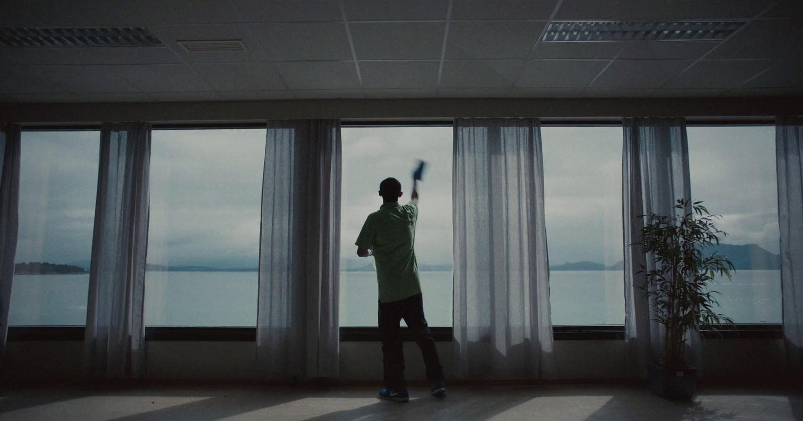 a man standing in front of a window holding a brush