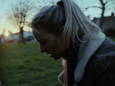 a woman standing in a field looking at a cell phone